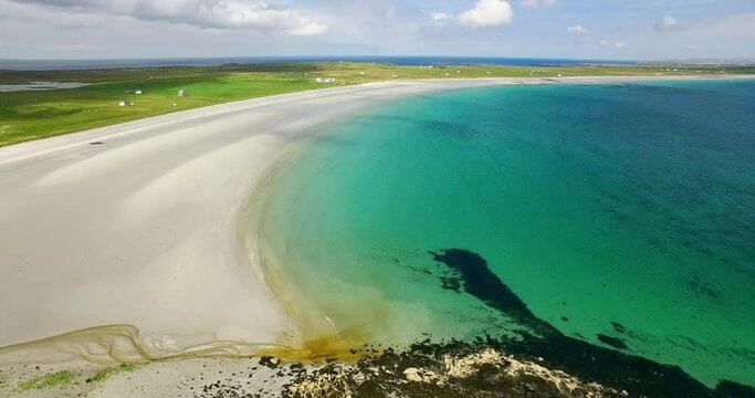 Aerial Panning Remote Scottish Beach And Coastline With Sand And Turquoise Colored Water Stretching To The Horizon Under Bright Blue Skies - Isle of Tiree, United Kingdom