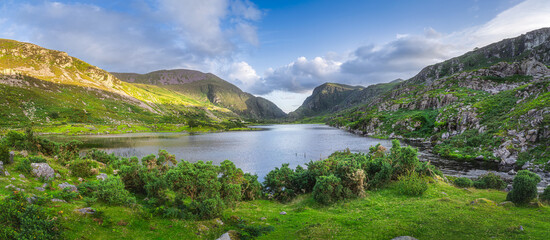 Large panorama with Black Lake valley and mountains at sunset in Gap of Dunloe, Black Valley, MacGillycuddys Reeks mountains, Ring of Kerry, Ireland