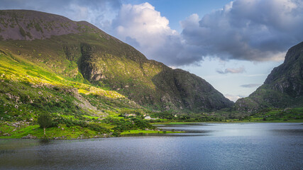 Mountains and Black Lake illuminated by sunlight at sunset in Gap of Dunloe, Black Valley, MacGillycuddys Reeks mountains, Ring of Kerry, Ireland