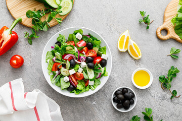 Fresh vegetable greek salad with lettuce, olives and feta cheese, top view