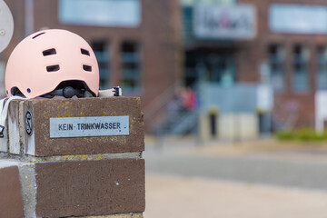 Mädchenfahrrad Helm auf der Randmauer eines öffentlichen Brunnens