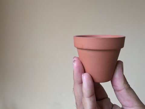 Mini Terracotta Pot Holding In Hand With A Copy Past Space And Solid Background Isolated Closeup