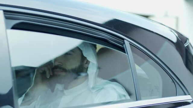 The sheik on the phone looks at the landscape.
