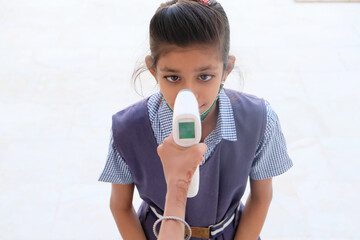 Indian schoolgirl getting a temperature check before going to school during the COVID-19 pandemic