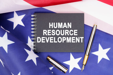 On the table is an American flag, a pen and a notebook with the inscription - HUMAN RESOURCE DEVELOPMENT