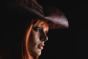 Beautiful female dummy in the pirate hat on a black background of shop showcase.