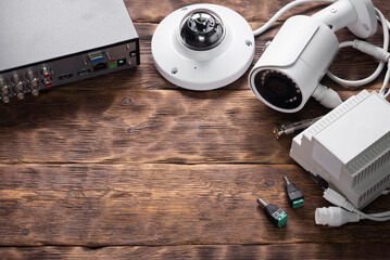 Modern video surveillance equipment on the wooden workbench background with copy space.