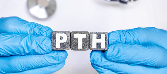 PTH Parathyroid hormone - word from stone blocks with letters holding by a doctor's hands in medical protective gloves