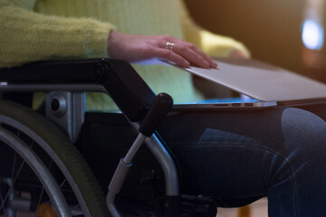 Young woman in wheelchair using computer laptop at modern workplace