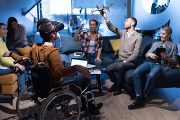 Fototapeta premium Disabiliti concept. Diverse group of architects witho one in wheelchair working in coworking office using modern technology.