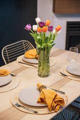 A bouquet of tulips on a four person dining room table.