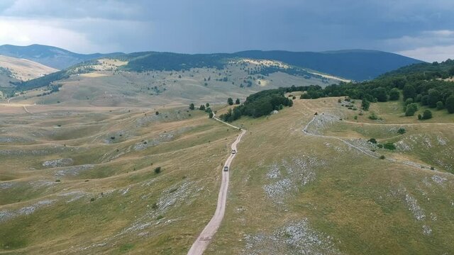 Aerial view on nature around village Vrdolje on the way to Lukomir in Bosnia and Herzegovina with two vintage off road cars going on the dirt road