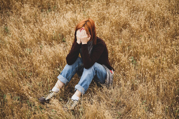 Naklejka na ściany i meble Lonely sad red-haired girl at field