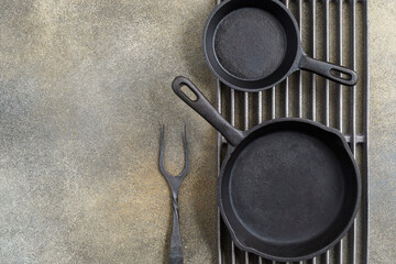 Grill grate with cast iron pans and fork on brown background with copy space. Food background