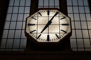 Beleuchtete eckige Uhr vor Fenster