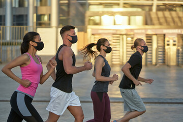 Fototapeta na wymiar Young mixed race running team in protective masks training