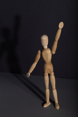 Wooden mannequin stands with raised hand on gray background. protest, attention concept. . copy space.