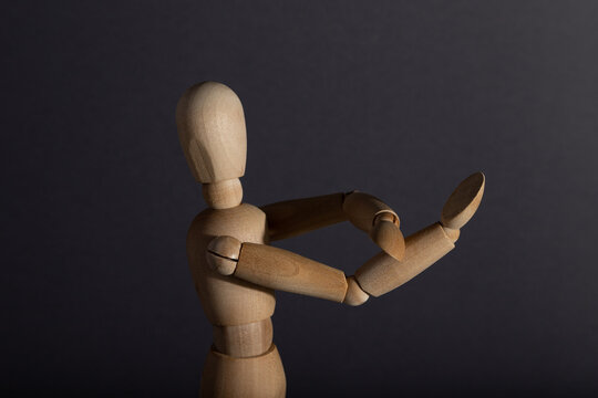 Wooden mannequin shows obscene gesture fuck off with hands on gray background. protest, riot, agression concept. copy space.