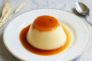 Cream caramel pudding with caramel sauce in plate on white rustic table