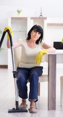 Senior old woman tired after vacuum cleaning house