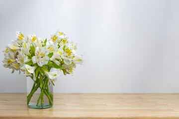 Florero con flores amarillas sobre mesa de madera.