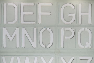 DEF GH MNO PQ alphabetical stencil on a white backlit surface