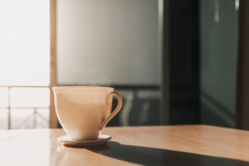 Hot cup of drink on the table in sun light of calm and warm morning.