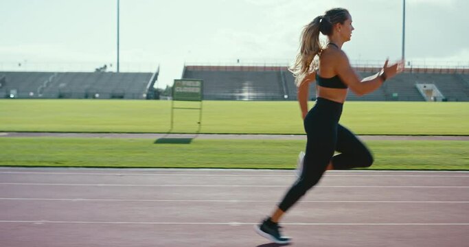 Young athletic woman running at stadium track, working hard and pushing the limits of her body, sprinting to the finish line, active lifestyle