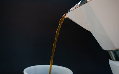 Serving coffee in a white mocha pot isolated on black background