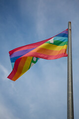 flag in rainbow colors flying against a clear blue sky in sunny weather