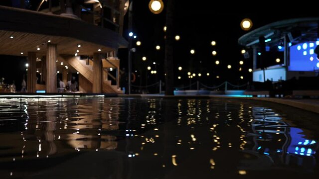 Reflection of disco lights on the water of the swimming pool. Holidays nightlife concept
