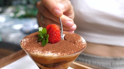 Close up of a spoon taking a piece of dairy free tiramisu decorated with strawberry. Classic Italian desserts in vegan option
