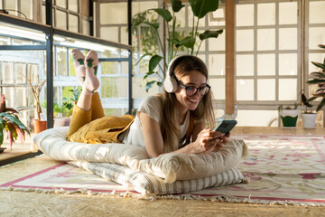 Female gardener relax after work lay on floor, listen music and surfing internet on smartphone app...