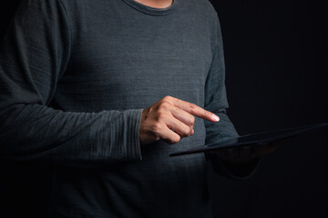 A young man's hand touched on a tablet, modern technology concept, empty space for text, studio photo on a black background.