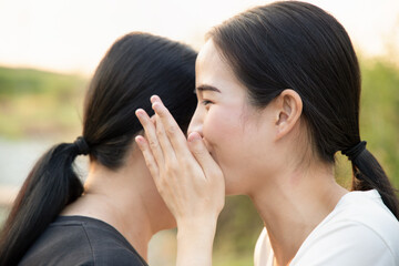 happy young woman gossiping with old senior woman, concept of good news, traditional mouth to mouth...