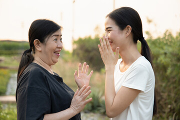 happy young woman gossiping with old senior woman, concept of good news, traditional mouth to mouth...