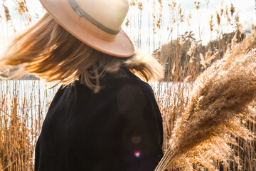 European blonde woman with beige hat in black sweater in the countryside. Golden hour, cottagecore....