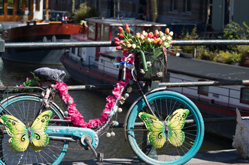 Fototapeta na wymiar A bicycle decorated with flowers on a canal in Amsterdam.