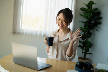 Joyful businesswoman sitting at desk looking at laptop screen talking with friend make informal video call