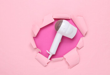 Stylish hair dryer on pink torn paper background. Minimalism fashion layout