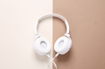 White stylish stereo headphones on brown beige background. Minimalistic music still life, music lover. Top view. Flat lay