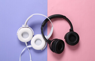 Two pairs of stereo headphones on pink purple background. Top view