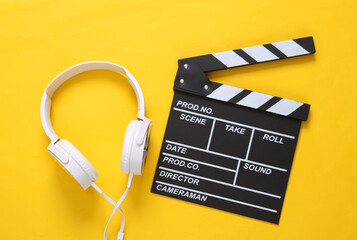 Clapperboard and headphones on a yellow background. Top view