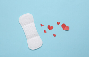 Feminine hygiene concept. Menstrual woman pads for hygiene protection in critical days with hearts on blue background. Top view. Flat lay