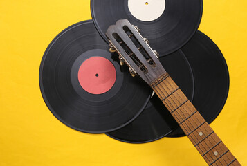 Acoustic guitar neck, vinyl record on yellow background. Musical concept. Minimalism. Top view....