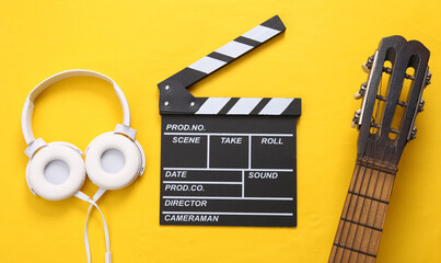 Guitar, clapperboard and headphones on a yellow background. Musical and movie concept