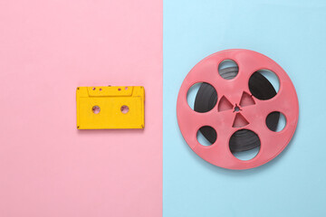 Pink retro audio reel and audio cassette on blue pink background. Minimalism music concept. Top view