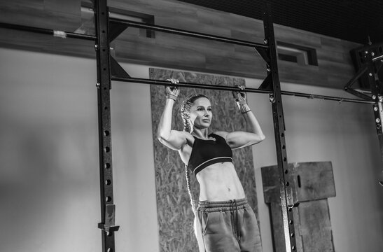 Athletic strong woman doing pull-ups on the horizontal bar in the gym