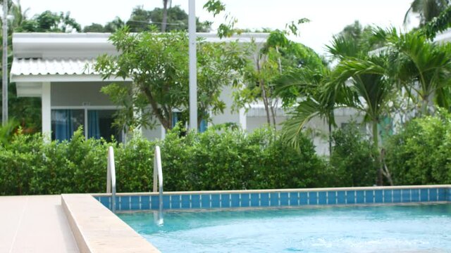 6 year old girl in a swimsuit jumps into the pool, resort in Thailand