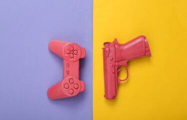 Gaming creative layout. Pink gamepad and pistol gun on purple yellow background. Top view. Flat lay